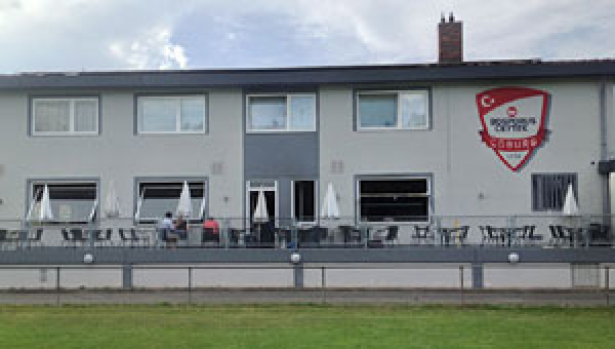 Das Vereinsgebäude des SV Bosporus Coburg mit großer Terrasse und Vereinslogo an der Wand.