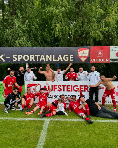 Mannschaft des SV Bosporus Coburg posiert lachend mit Banner „Aufsteiger Saison 2024/25“ auf dem Fußballfeld.